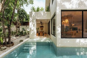 A modern building with a swimming pool, a wooden bench, and a hanging chair. - Tulumaya Boho Luxe Villa in Aldea Zama Concierge (Tulum)