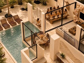 Un espace aménagé au bord de la piscine, comprenant un coin repas, des chaises longues et une vue sur la piscine.