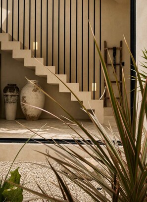 A staircase with a minimalist design, leading to a landing area with two large vases and a wooden ladder. - Tulumaya Boho Luxe Villa in Aldea Zama Concierge (Tulum)