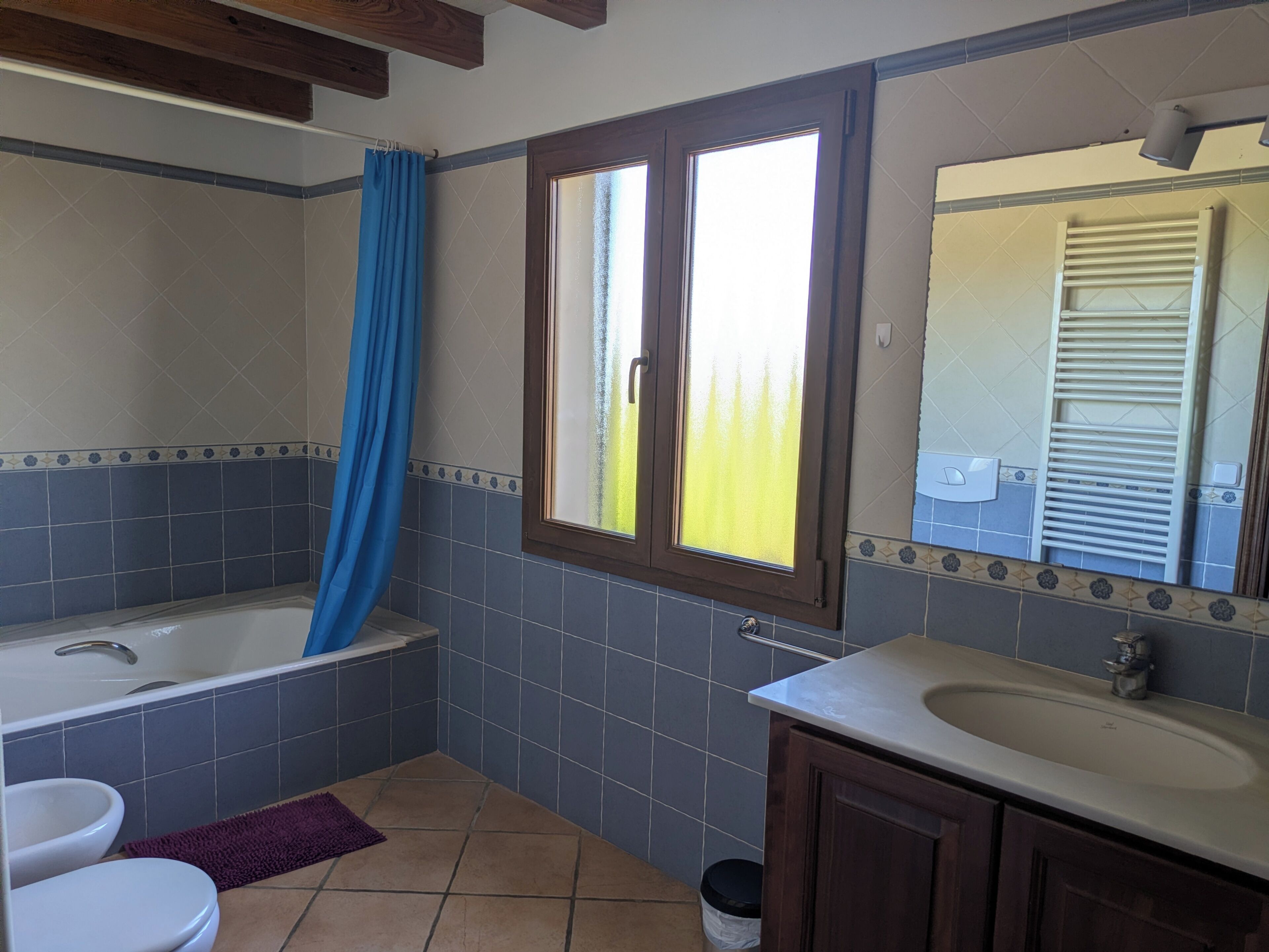 A bathroom with a bathtub, a sink, a toilet, and a window with a view.