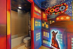 Een badkamer met toilet, een douchegedeelte en een muurschildering van een hond en de tekst 'Coco'.