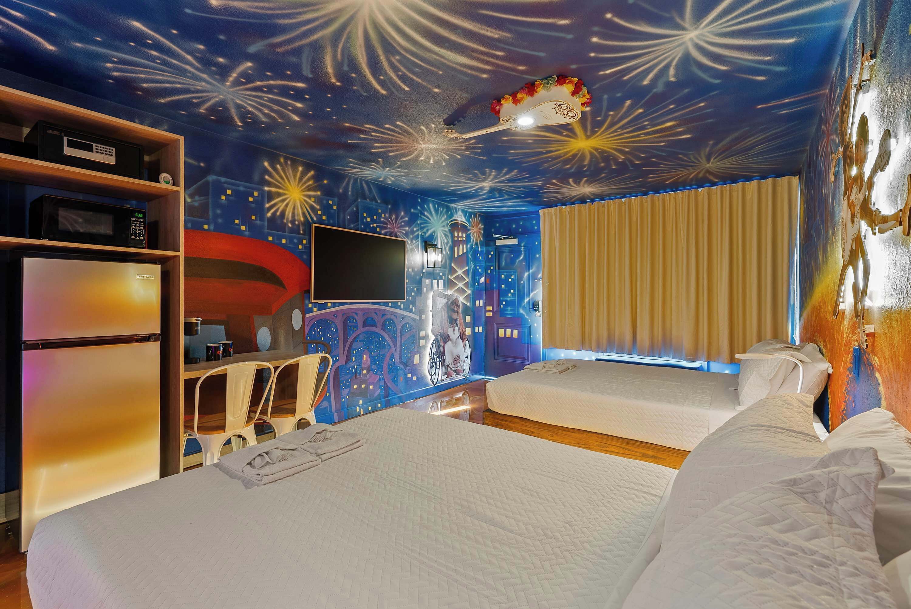 A hotel room with two beds, a flat-screen TV, a microwave, a refrigerator, a ceiling mural, and a window with curtains.