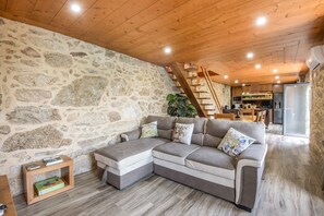 Ein gemütlicher Wohnbereich mit Steinwand, Holzboden und einer Eckcouch.