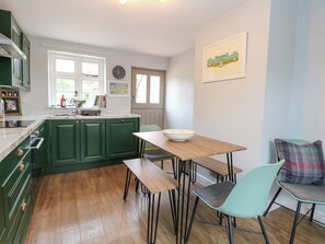 A kitchen with green cabinets, a wooden dining table, and a bowl on it. - The Mallows (Walsingham)