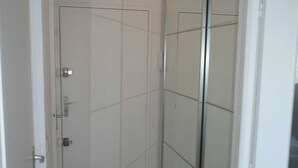 Um quarto com porta fechada, puxador visível e chão de azulejos.