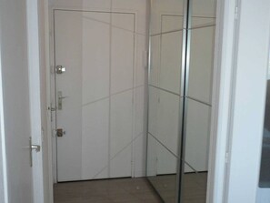 Una habitació amb la porta tancada, un mànec visible i un sòl de rajoles.
