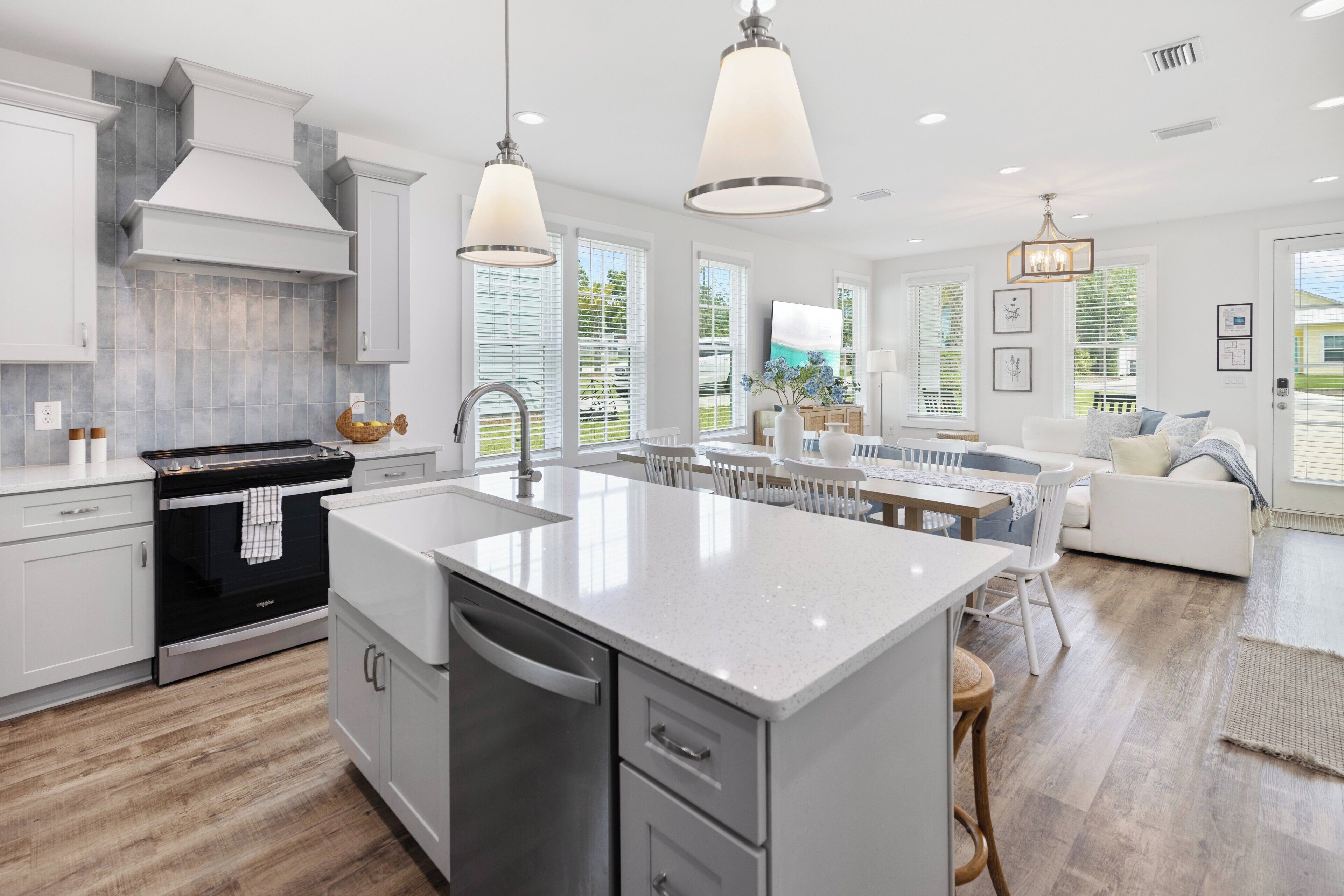 A modern kitchen with a central island, white cabinetry, and pendant lighting.