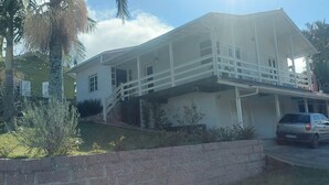 Una casa de dos pisos con balcón, entrada para coches y vehículos estacionados.