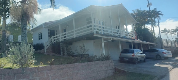 A two-story house with a balcony, a driveway, and parked cars.