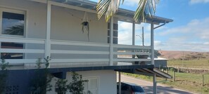 Ein zweistöckiges Gebäude mit Balkon, Fenster mit Blick und einer Tür.