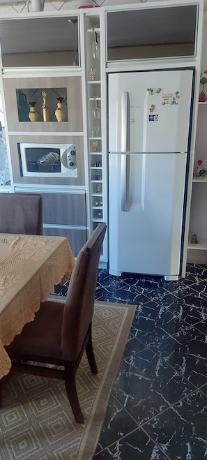 A kitchen with a refrigerator, microwave, and decorative items.