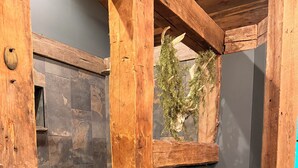Ein rustikales Badezimmer mit einer Steindusche, Holzbalken und einem alten Eimer.