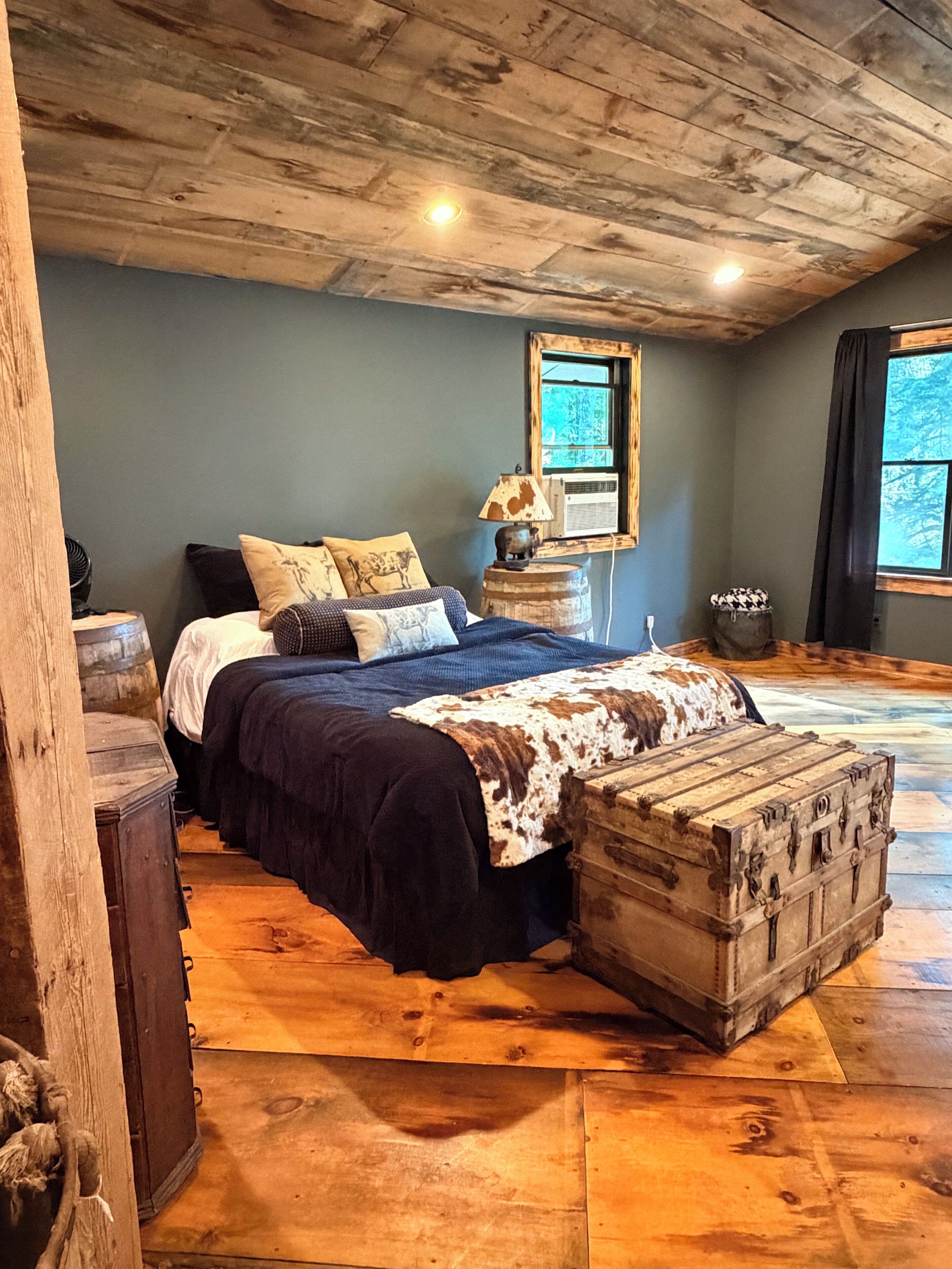 Ein Schlafzimmer mit einem großen Bett, einem Holzkopfteil und einer rustikalen Kommode.