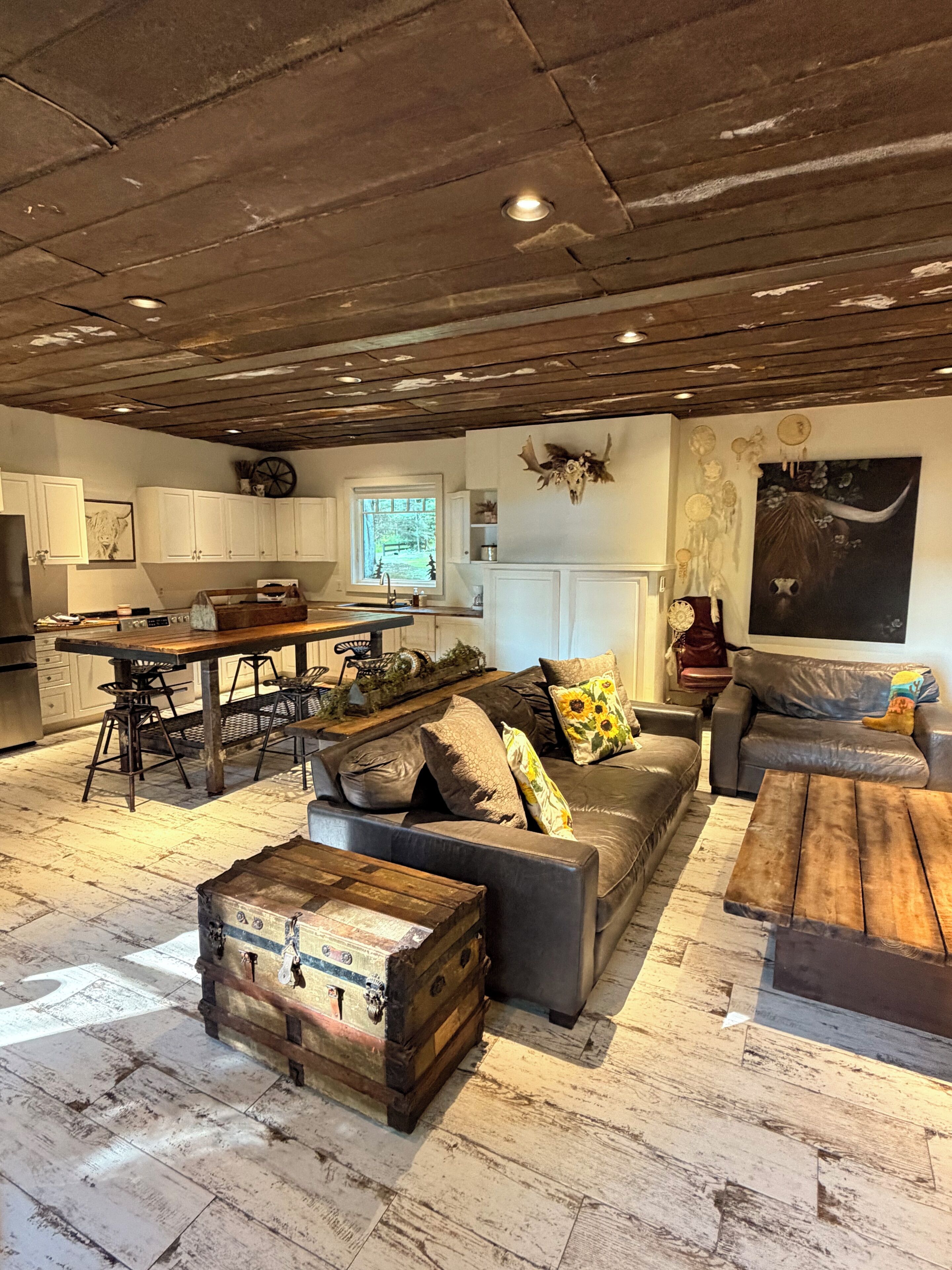 A rustic interior with a dining area, sofa, and a large wooden chest.