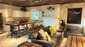 A rustic interior with a dining area, sofa, and a large wooden chest.