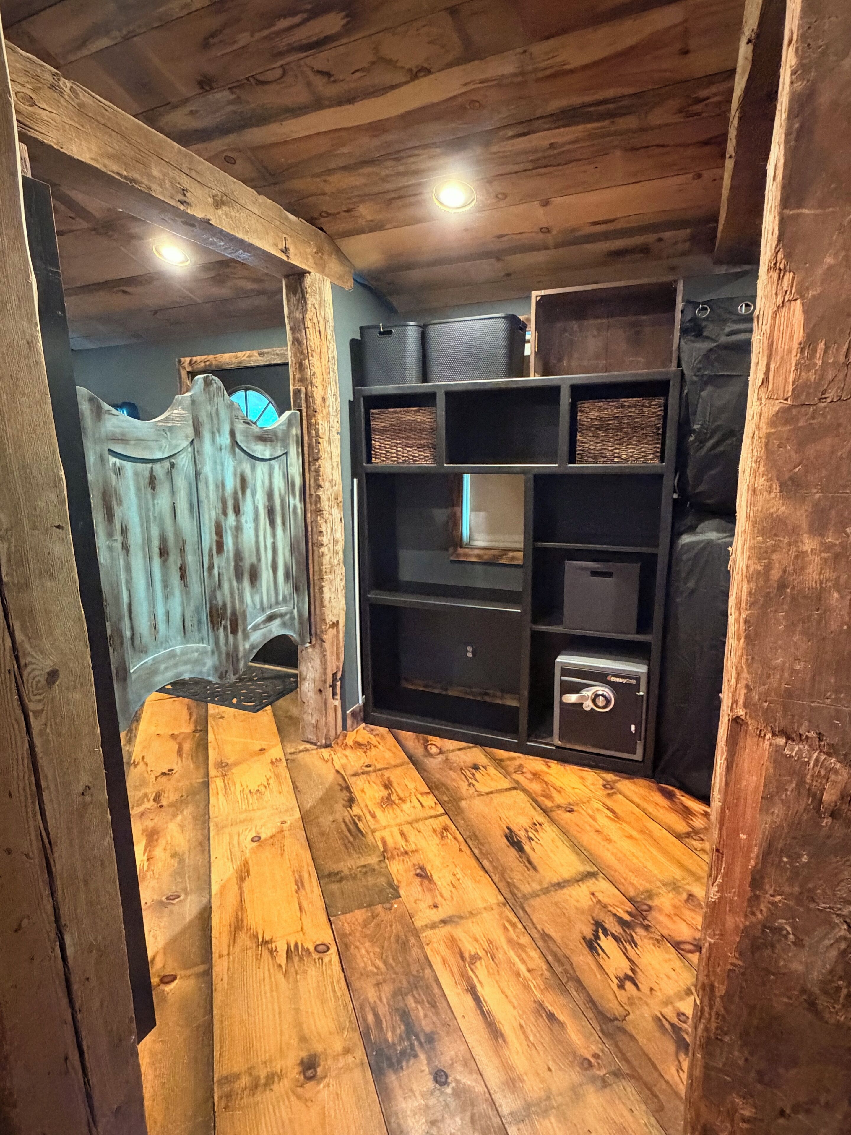 A room with wooden flooring, a built-in bookshelf, and a small safe.