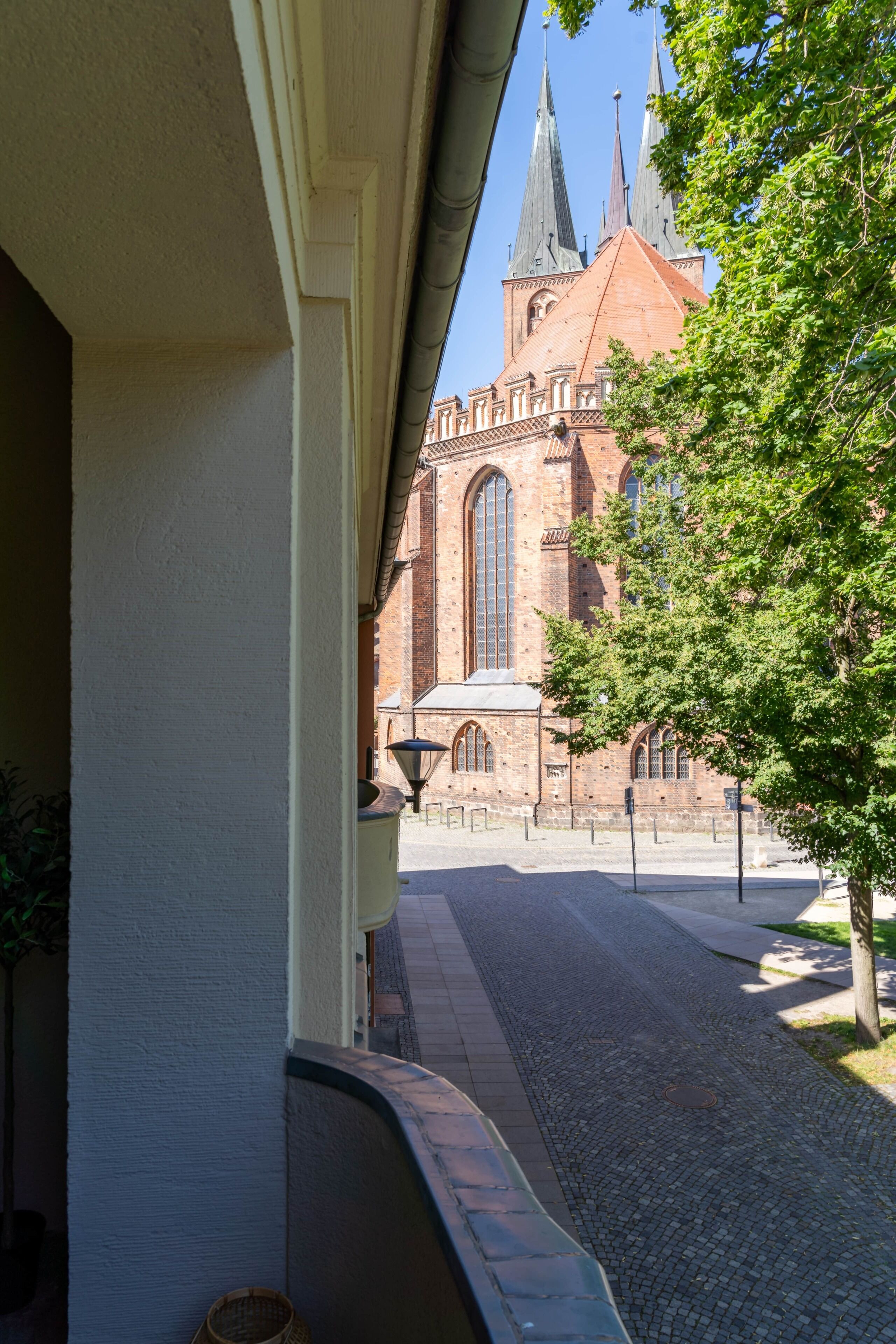 A cobblestone street leading to a historic building with a large arched window and multiple spires.