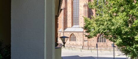 A cobblestone street leading to a historic building with a large arched window and multiple spires.