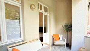 A covered patio with a wooden bench, a cushioned sofa, and a chair. - Beautiful 3-bedroom Apartment 'Johann' (Stendal)
