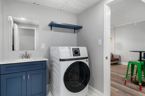 Ein Waschraum mit einer Waschmaschine, einem Waschbecken und einem blauen Schrank.