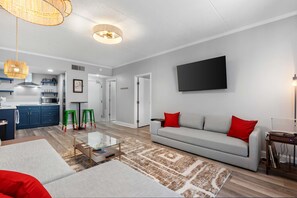 Ein modernes Wohnzimmer mit einer Couch, einem Couchtisch und grünen Hocker.