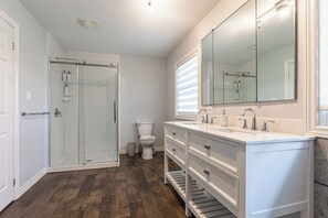 A bathroom with a glass shower enclosure, a toilet, a vanity with a large mirror, and a wooden floor. - Cottage Style living within city limit! (London)