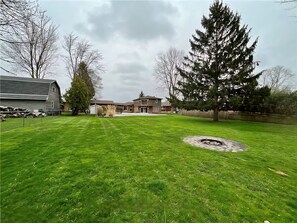 A residential area with a well-maintained lawn, a large tree, and a house in the background. - Cottage Style living within city limit! (London)