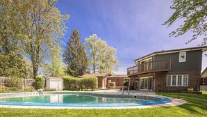 Um bairro residencial com piscina, uma casa de dois andares e um pequeno galpão.