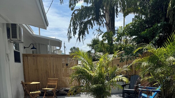 Un patio con suelo empedrado, mobiliario exterior y plantas en macetas.