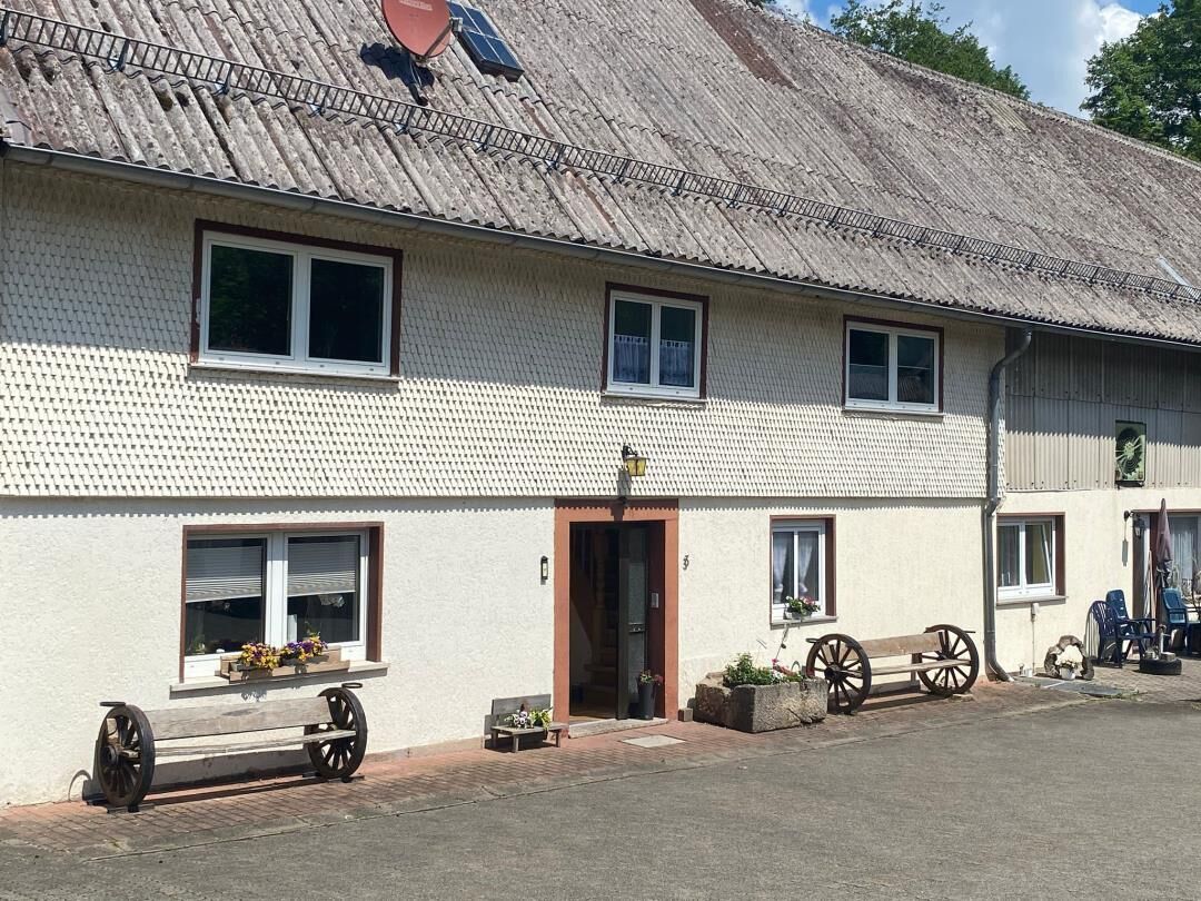 Ein zweistöckiges Gebäude mit einem Ziegeldach, einer Haustür und Fenstern.