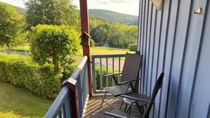 A wooden deck with a railing, two chairs, and a view of a green landscape with trees and hills. - NEW! Vacation apartment Nino (Rötz)