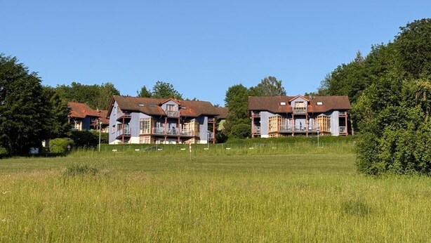 A row of two-story buildings with balconies, set in a grassy field with trees in the background. - NEW! Vacation apartment Nino (Rötz)