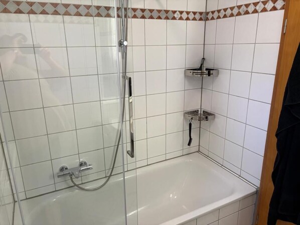 A bathroom with a glass-enclosed shower, a separate bathtub, and a towel rack.