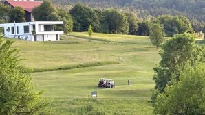 A golf course with a modern building in the background, a golf cart, and a person walking. - NEW! Vacation apartment Nino (Rötz)