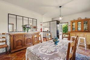 A dining area with a table set for four, wooden chairs, a cabinet with glass doors, and a large mirror above the mirror. - Casa da Aldeia - Vale de Cambra (Arões)