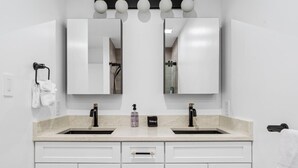 A bathroom with two sinks, a mirror, and a towel rack. - Freshly Renovated 2BR in E Austin High End Finishes Near Downtown Nightlife (Austin)