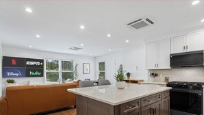 A modern kitchen with white cabinets, a black stove, and a large island. - Freshly Renovated 2BR in E Austin High End Finishes Near Downtown Nightlife (Austin)