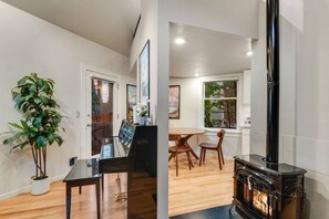 Ein modernes Interieur mit Holzboden, einem Essbereich mit Stühlen, einem schwarzen Herd und einem Blumentopf.