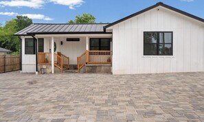 A single-story building with a porch, a staircase, and a fenced yard. - Your Cozy E Austin Retreat | New High-End 2BR Mins to Dining, Downtown & Pubs (Austin)