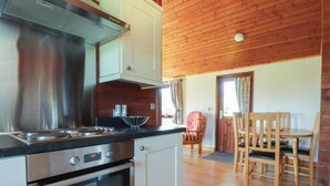 A kitchen with stainless steel appliances, wooden flooring, and a dining area with wooden furniture. - Chestnut Lodge (Preston)
