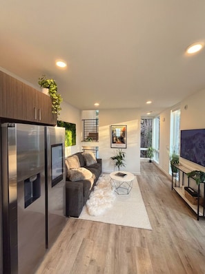 A modern living room with a sofa, coffee table, and a flat-screen TV. - Capitol Hill Rooftop Hot Tub Close to Light Rail (Seattle)