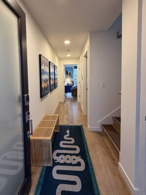 A hallway with a wooden bench, a snake-patterned rug, and framed pictures on the walls. - Capitol Hill Rooftop Hot Tub Close to Light Rail (Seattle)