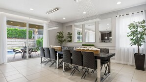 Un comedor moderno con una mesa larga, sillas y vistas a una piscina.