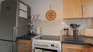 A kitchen with a refrigerator, stove, oven, and various kitchen utensils. - 39 Knocknagael (Inverness)