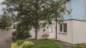 A residential building with a tree in the front yard, a small garden, and a visible door with a number. - 39 Knocknagael (Inverness)