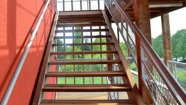 A wooden staircase with metal railings leading to an upper level. - Eklo Hotels Le Mans (Le Mans)
