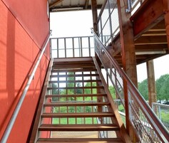 Una escalera de madera con barandillas de metal que sube a un nivel superior.