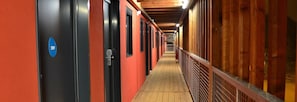 A corridor with doors, a wooden floor, and a metal railing.