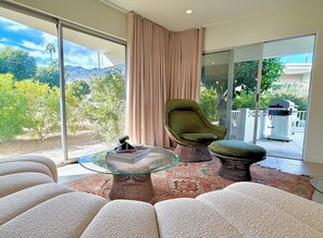 Ein modernes Wohnzimmer mit einem Glastisch, einem grünen Sessel und einem Sofa.