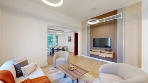 Un salon moderne avec un canapé, des fauteuils, une table basse et un téléviseur fixé au mur.